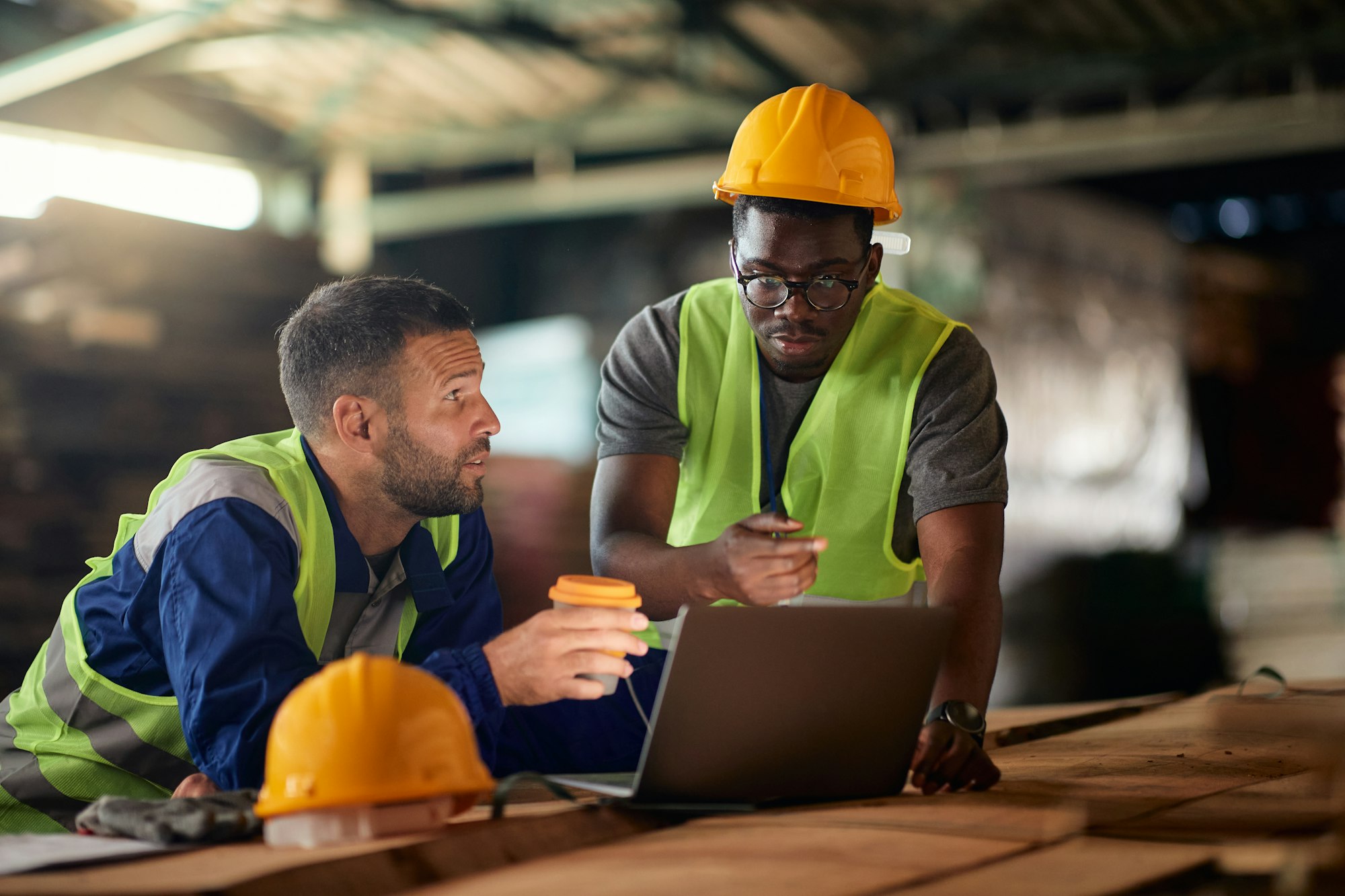 Multiracial warehouse workers using laptop during their coffee break.